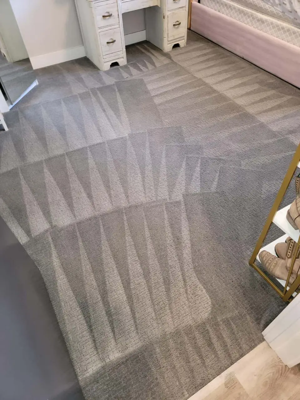 Real job photo: gray bedroom carpet cleaned in overlapping fan-shaped passes, the cleaned bands lighter and the carpet not yet reached darker.